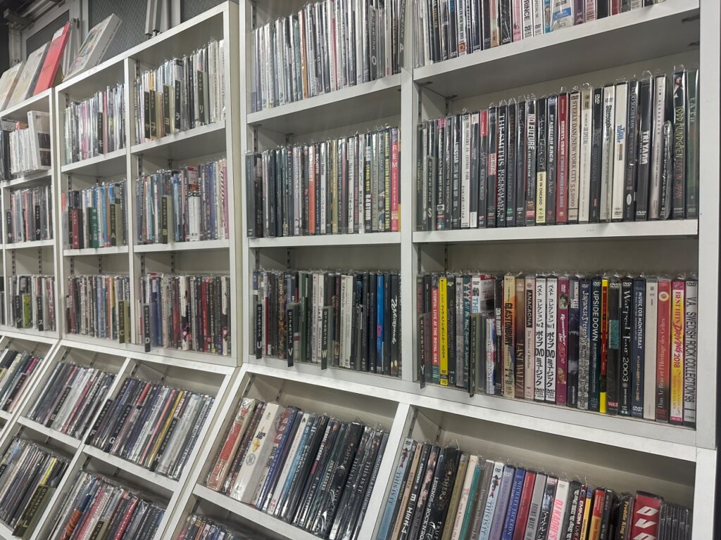 CDやDVD、Blu-rayが棚いっぱいに並ぶレコードショップの在庫棚