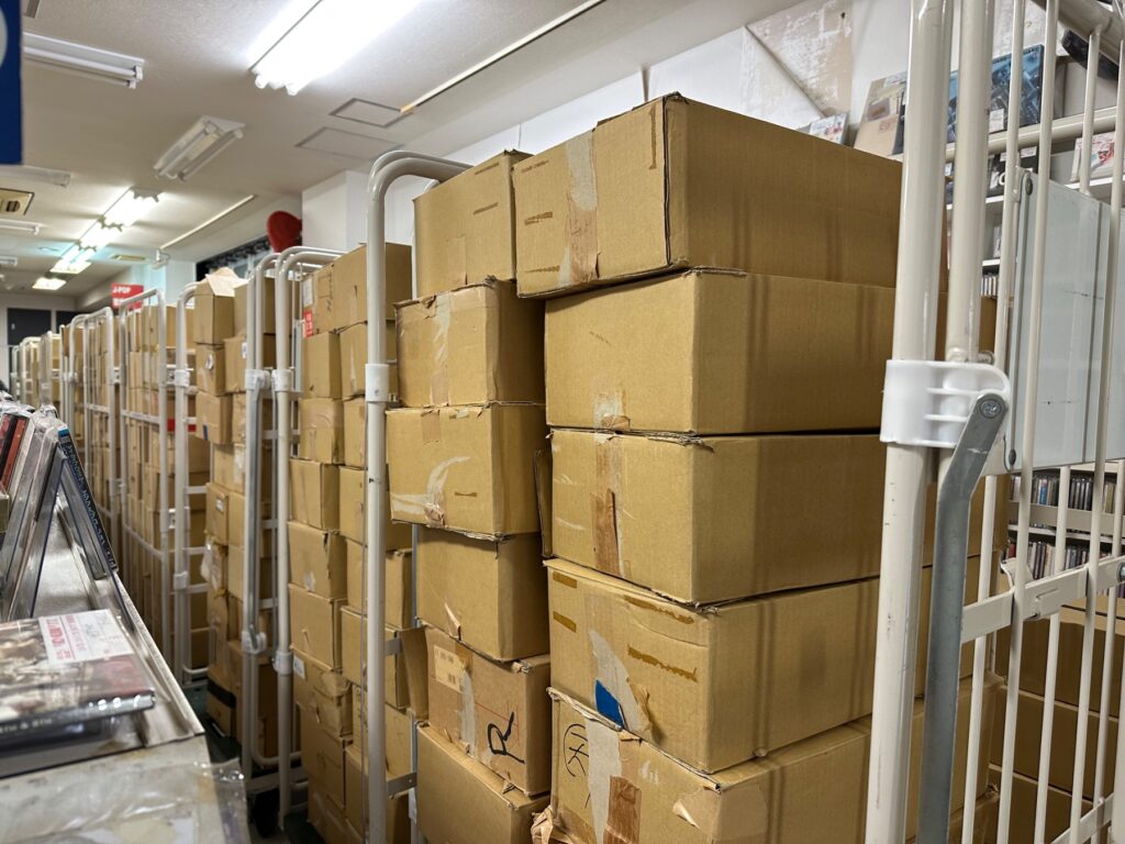 レコード店の在庫が詰まった段ボール箱が通路いっぱいに積まれている様子