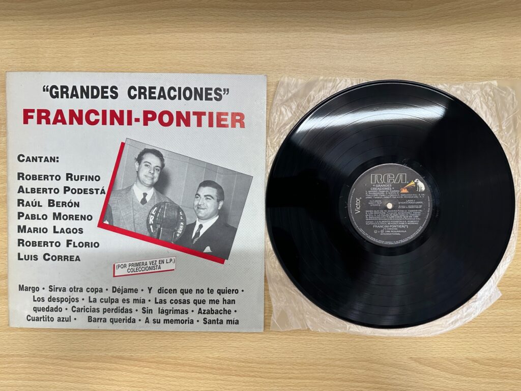 『Grandes Creaciones』のジャケットと黒いLPレコードが木製の机に並べられている