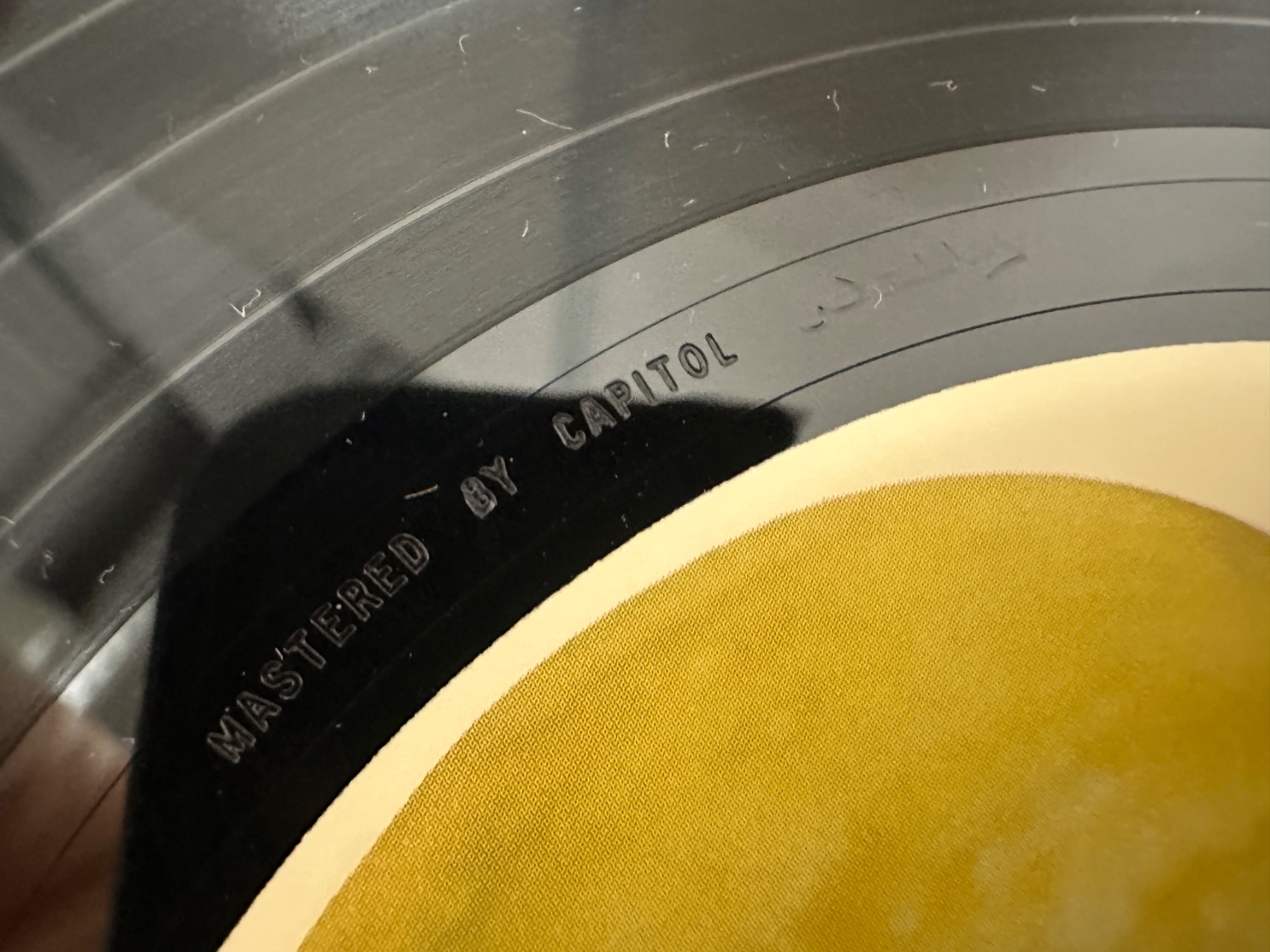 レコード盤の溝と黄色いラベルの接写。盤面に「MASTERED BY CAPITOL」と刻印されている。